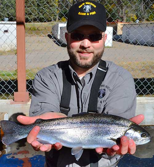 Scott Bernard, manager, shows off a large rainbow trout raised at the New Mexico Department of Game and Fish Lisboa Springs Fish Hatchery.