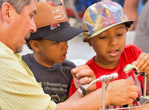 Become a Wildlife Conservation Volunteer. (Photo of fishing instructor helping youth). New Mexico Department of Game and Fish