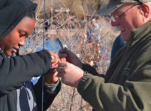 Become a Wildlife Conservation Volunteer. (Photo of fishing instructor helping youth). New Mexico Department of Game and Fish