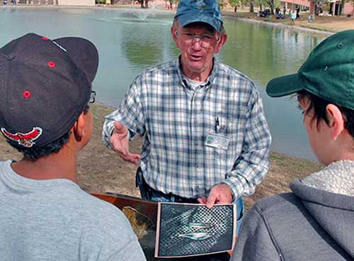 Become a Wildlife Conservation Volunteer. (Photo of fishing instructor helping youth). New Mexico Department of Game and Fish