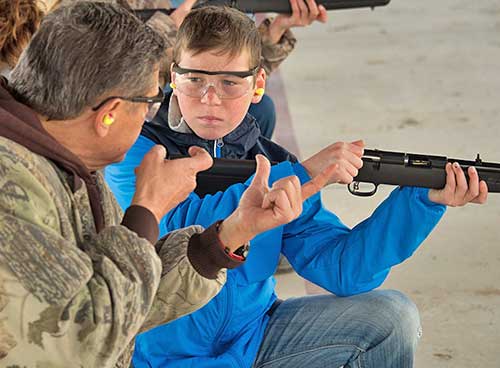 Become a Wildlife Conservation Volunteer. (Photo of hunting instructor helping youth). New Mexico Department of Game and Fish