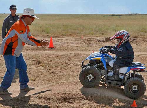 Become a Wildlife Conservation Volunteer. (Photo of off-highway vehicle instructor helping youth). New Mexico Department of Game and Fish